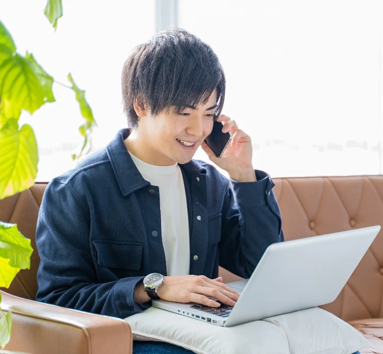 男性が在宅でパソコンを見ながら他の人とやり取りをしている様子